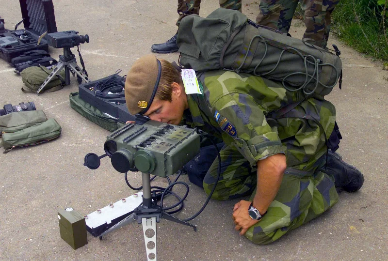Svensk soldat med svensk flagga på uniformen studerar optisk utrustning i Kosovo, 2002.